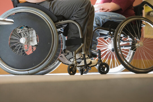 Low section view of a man with Muscular Dystrophy and a woman sitting in wheelchairs