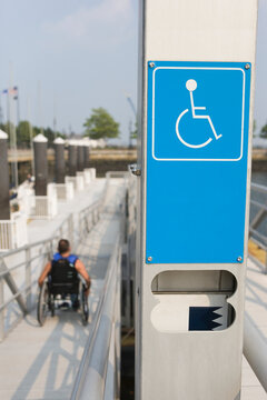 Close-up of a Disabled signboard with a man sitting in wheelchair in the background