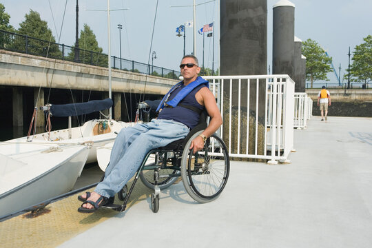 Mature man sitting in a wheelchair at a harbor for adaptive sailing