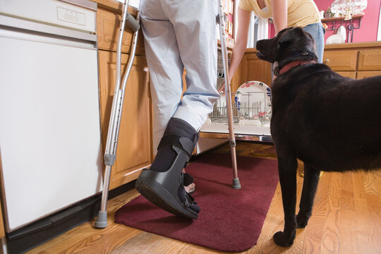 Low section view of a disabled woman standing in the kitchen near a dog
