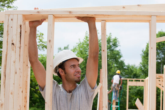 Carpenter lifting a board on framing