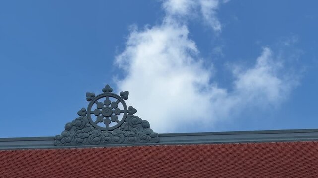 Vertical view shows Buddhist flag moving freely on tall flagpole against clear blue sky. Cultural heritage.