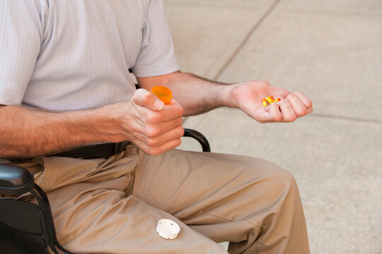 Man with Friedreich's Ataxia holding pills with degenerated hands