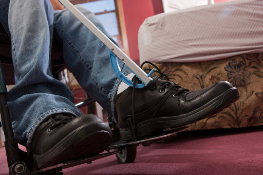 Man with spinal cord injury taking off his shoes with an extension tool