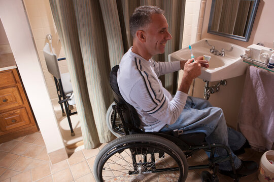 Man with spinal cord injury in a wheelchair brushing his teeth
