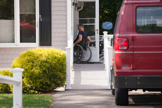 Man with spinal cord injury in a wheelchair going up home ramp