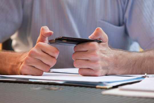 Businessman with Friedreich's Ataxia text messaging on a mobile phone with hand degeneration
