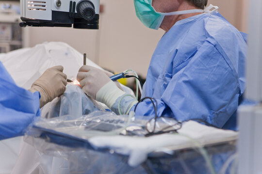 Surgical technologist irrigating eye and doctor using phaco with cracker instrument during cataract