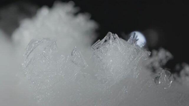 Bright point light appearing behind vapor, clearing mist and revealing ice crystals in studio