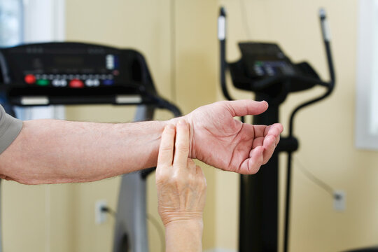 Woman checking pulse rate of man in the gym
