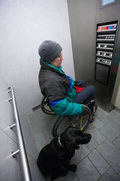Woman with multiple sclerosis using an elevator with a service dog