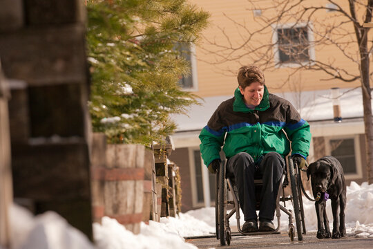 Woman with multiple sclerosis in a wheelchair with a service dog in winter