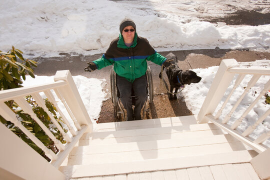 Woman with multiple sclerosis trying to get up stairs with a service dog