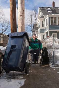 Woman with multiple sclerosis doing recycling with a service dog in winter