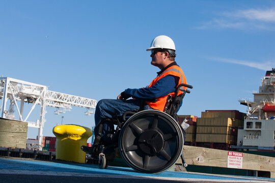 Transportation engineer in a wheelchair inspecting shipping containers at shipping port
