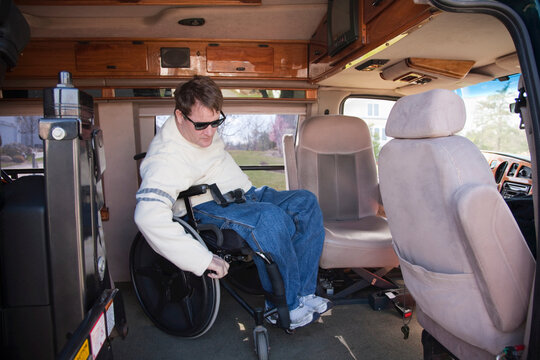 Man with spinal cord injury getting into the driver's seat from his wheelchair in accessible van