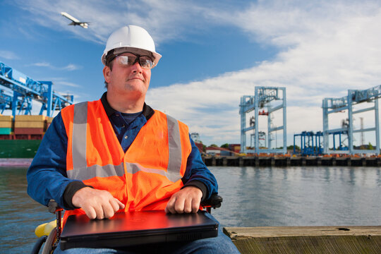 Transportation engineer in wheelchair with a laptop at shipping port