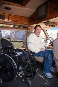 Man with spinal cord injury getting into the driver's seat from his wheelchair in accessible van