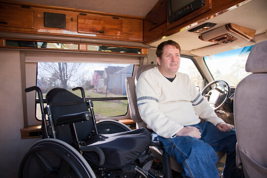 Man with spinal cord injury getting into the driver's seat from his wheelchair in accessible van