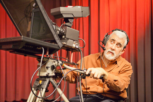 Man in wheelchair with muscular dystrophy using a TV camera and a teleprompter in studio