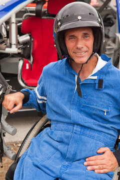 Disabled race car driver with spinal cord injury in wheelchair with his modified race car