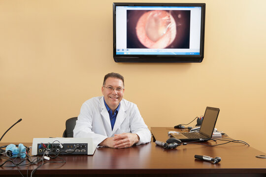 Portrait of an audiologist with his examination instruments and computer screen