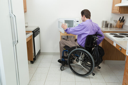 Man in wheelchair with spinal cord injury opening accessible microwave