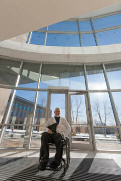 Doctor with muscular dystrophy in wheelchair at hospital entrance