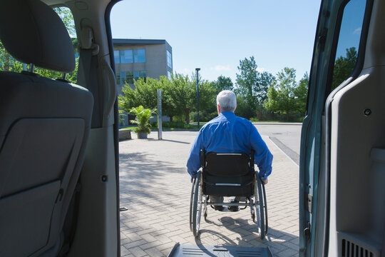 Senior man in wheelchair exiting a vehicle from a ramp