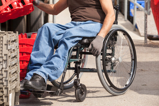 Loading dock worker with spinal cord injury in a wheelchair stacking inventory trays