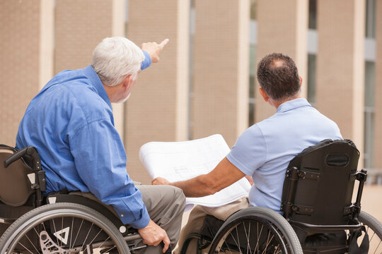 Design engineers reading Plans, one with muscular dystrophy and one with a spinal cord injury