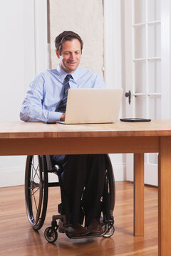 Businessman with spinal cord injury in a wheelchair working on laptop