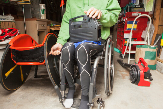 Wheelchair racer with spinal cord injury preparing wheelchair tires for a race