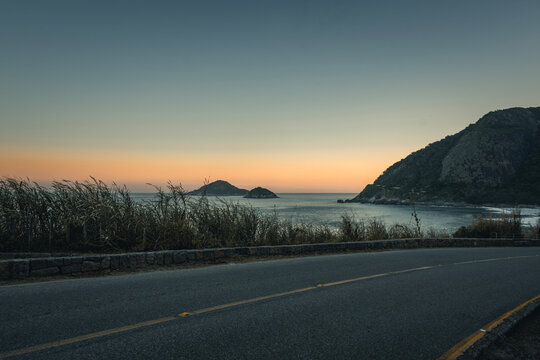 Vista panor&acirc;mica do oceano durante o crep&uacute;sculo com ilhas ao fundo e tons suaves no c&eacute;u, Praia de Grumari, Rio de Janeiro