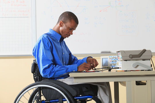 Engineering student sitting in a wheelchair preparing lab experiment with oscilloscope and
