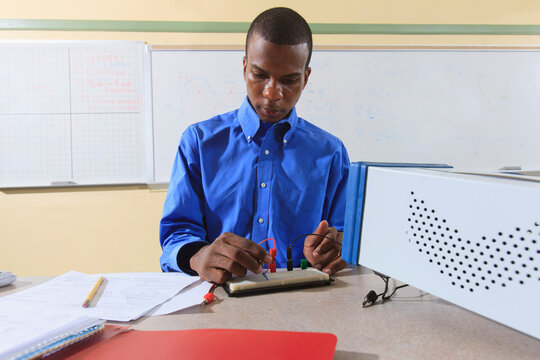 Engineering student in an electronics classroom in a wheelchair from Spinal Meningitis preparing a