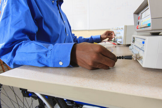 Engineering student in an electronics classroom in a wheelchair from Spinal Meningitis preparing a