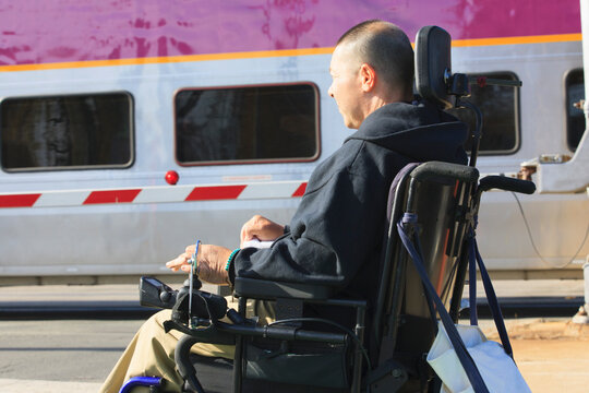 Man with spinal cord injury using his motorized wheelchair waiting for public train