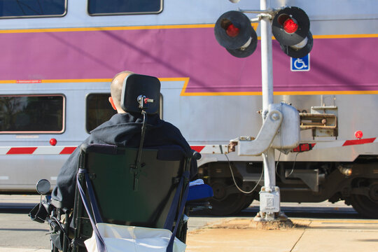 Man with spinal cord injury using his motorized wheelchair waiting for public train