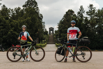 Fototapeta premium Two cyclists posing with gravel bicycles during an outdoor journey. Active travel and adventure lifestyle concept