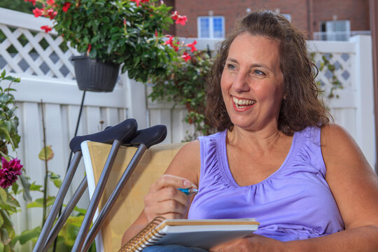 Woman with Spina Bifida writing notes while relaxing on patio