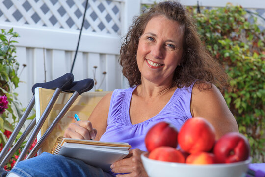 Woman with Spina Bifida writing notes while relaxing on patio