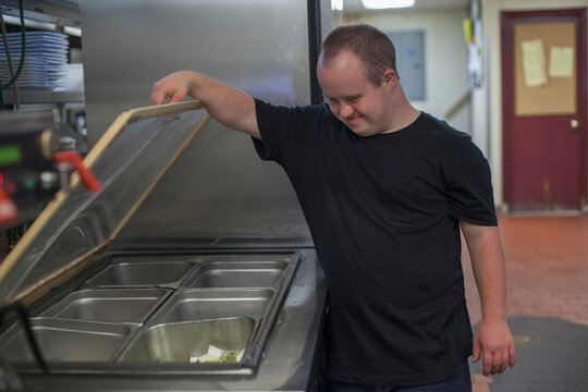 Waiter with Down Syndrome working in the kitchen of a restaurant