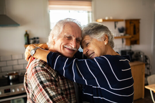 Happy senior couple hugging in cozy kitchen