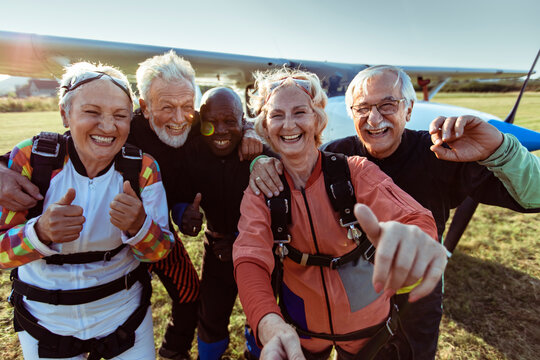 Smiling senior friends taking skydiving selfie at airfield