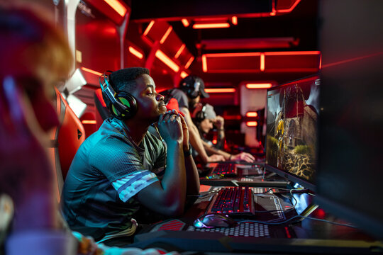 Focused gamers competing at pcs in neon esports arena