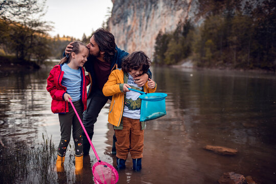 Parent with two children wading and net fishing in mountain lake