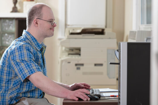 Man with Down Syndrome working at a computer in an office