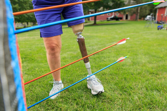 Woman with prosthetic leg pulling arrows from target after archery practice