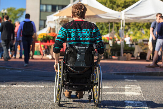 Trendy man with a spinal cord injury in wheelchair at a city outdoor market
